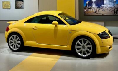 Yellow sports coupe displayed indoors with sleek design.