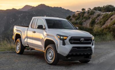 A white pickup truck parked in a scenic mountainous area at sunset.