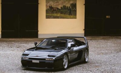 A sleek black sports car parked in an elegant courtyard.