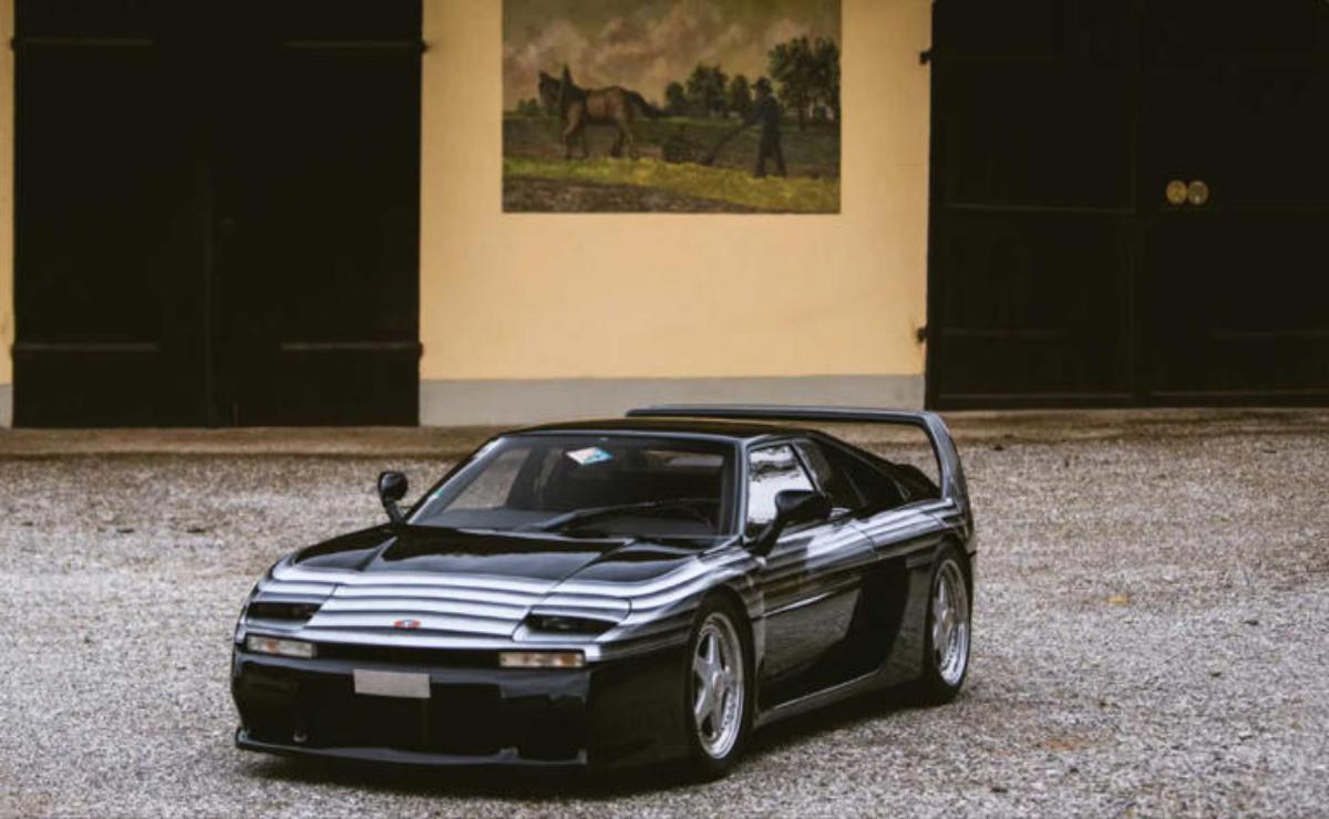 A sleek black sports car parked in an elegant courtyard.