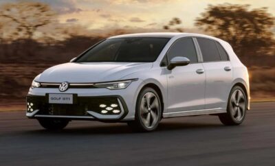 A sleek white Volkswagen Golf driving on a road at sunset.