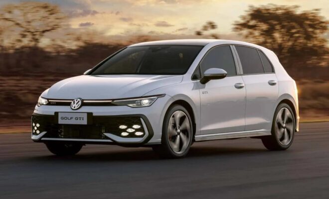 A sleek white Volkswagen Golf driving on a road at sunset.