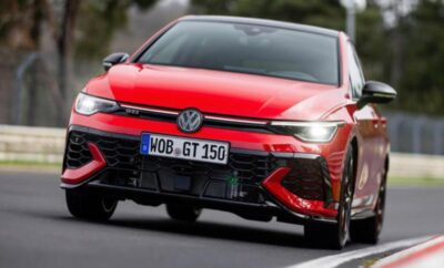 Red sports car speeding on the road with aggressive front design.