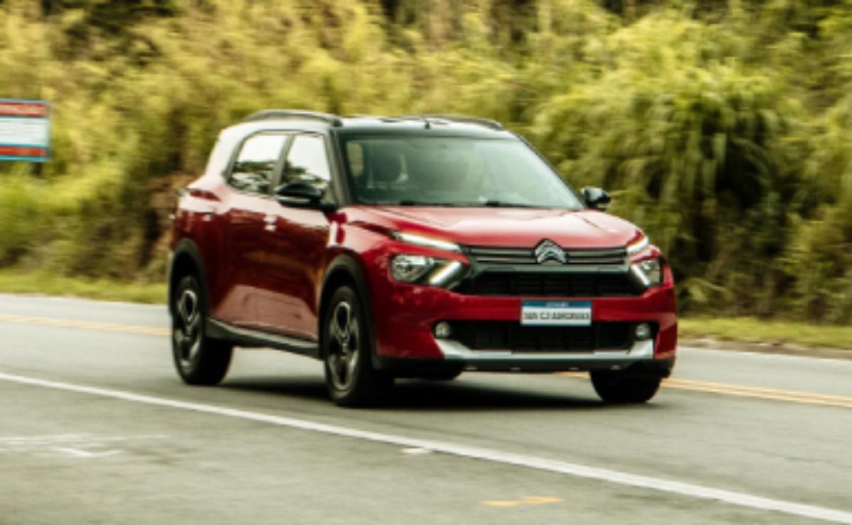 Red Citroën SUV driving on a road with greenery.