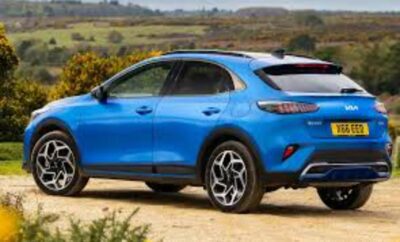 Blue compact SUV parked on a dirt path with countryside background.