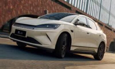 White electric SUV parked near a building with modern design.
