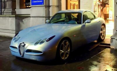A sleek silver sports car parked on a city street at night.