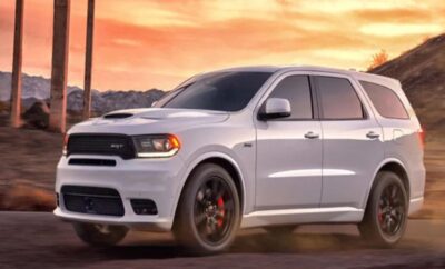 A sleek white SUV parked with a vibrant sunset in the background.