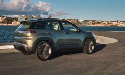A sleek gray SUV driving along a coastal road with a scenic ocean view.