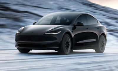 A sleek black Tesla Model Y driving on a snowy road.