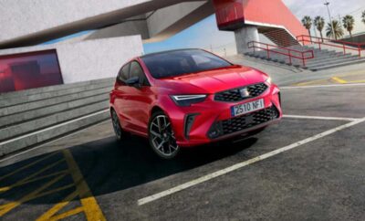 A red compact hatchback car parked near stairs in an urban setting.