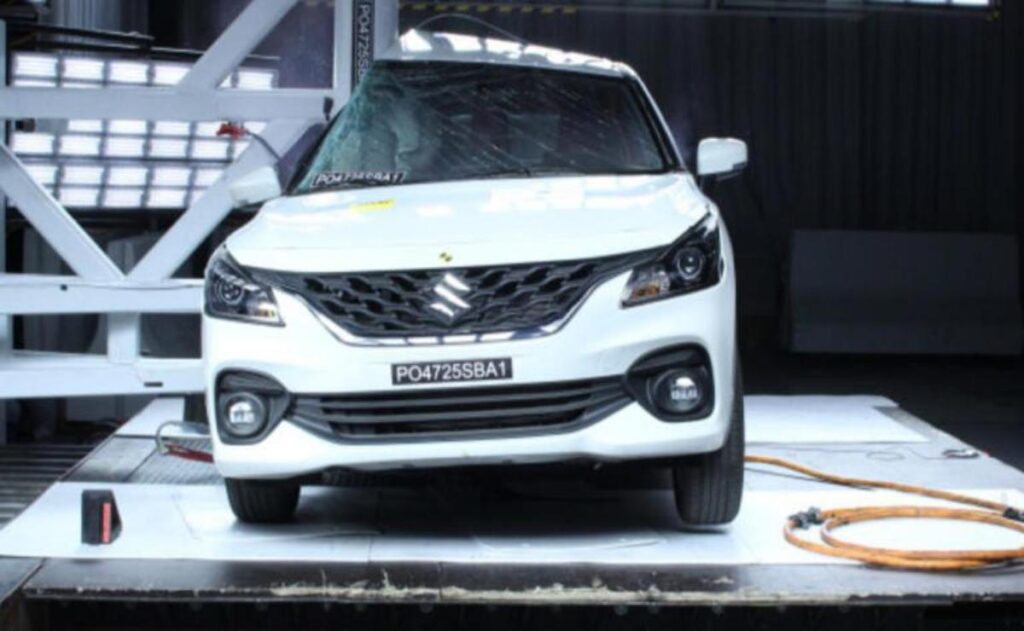 A man working on his laptop and writing in a notebook at a desk.