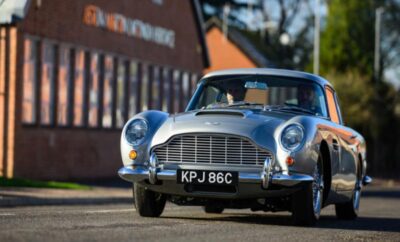 Classic silver Aston Martin parked outdoors on a sunny day.