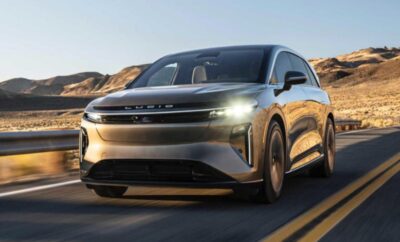 A sleek modern electric car on a road with mountains in the background.
