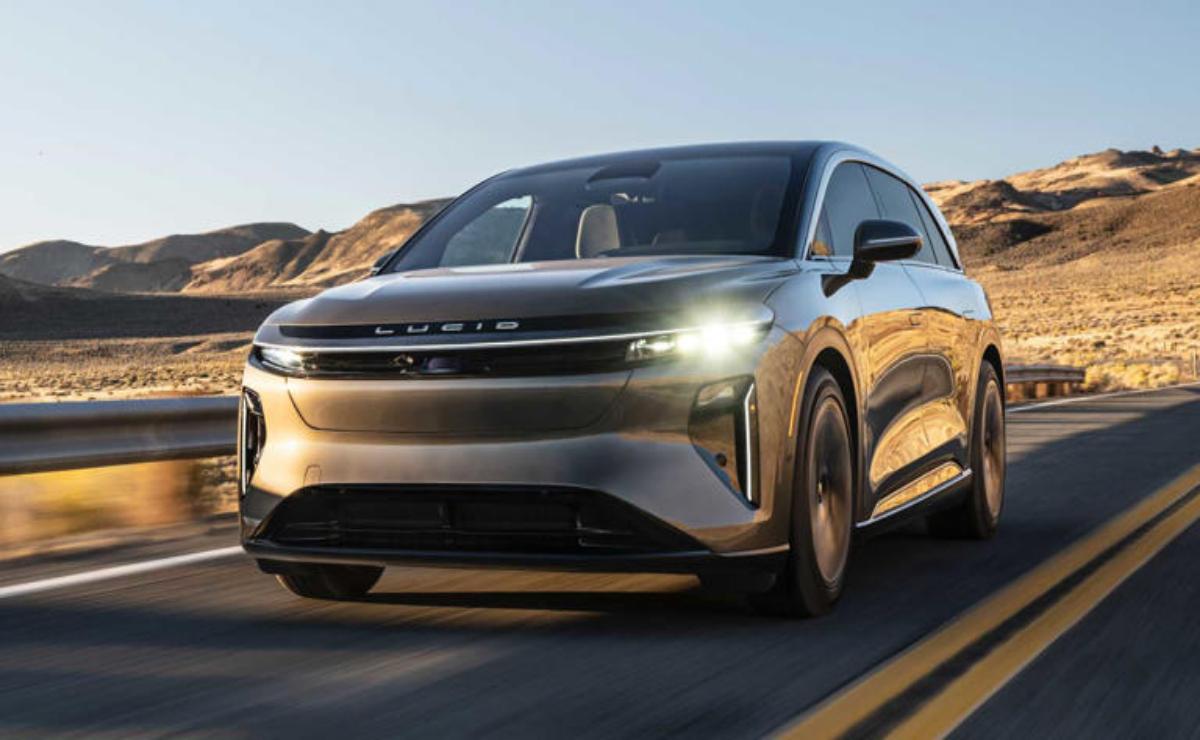 A sleek modern electric car on a road with mountains in the background.