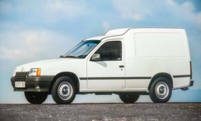 White compact cargo van parked outdoors against a cloudy sky.