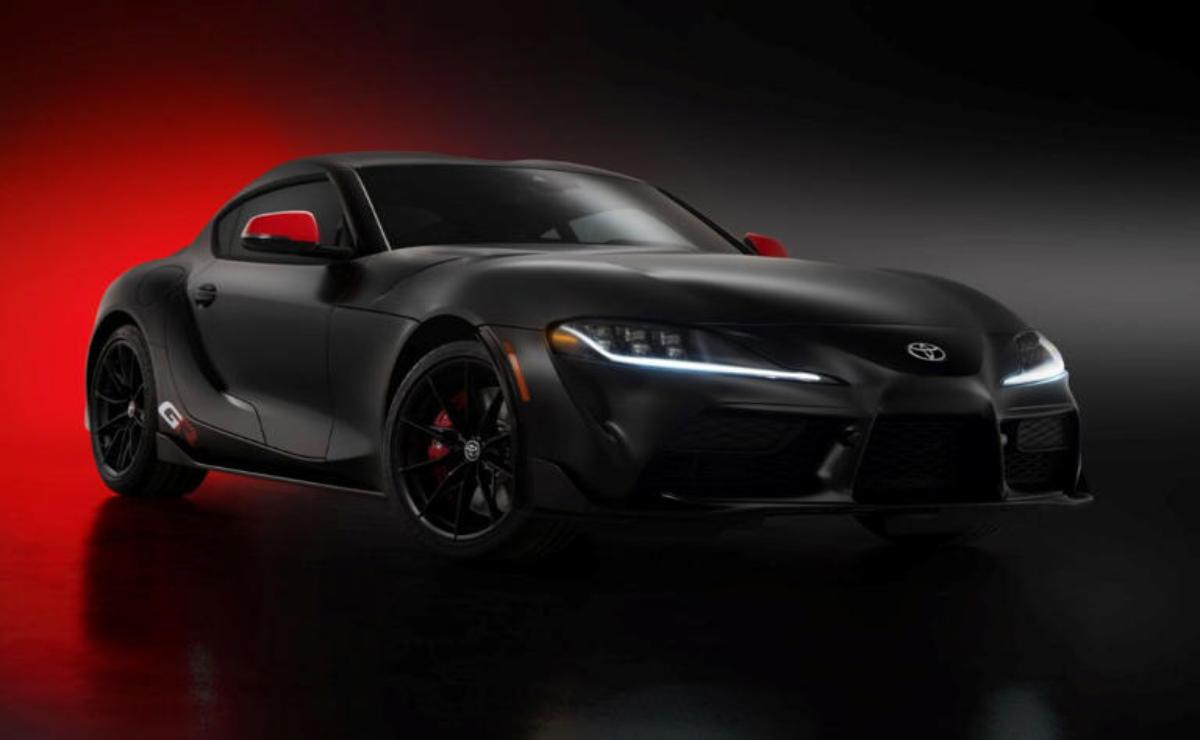 Sleek black sports car with red accents in a dark setting.
