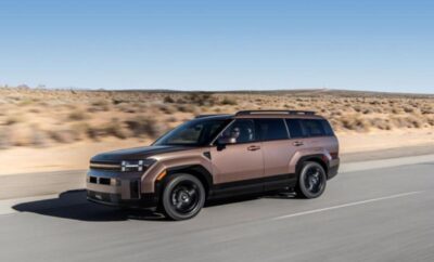 A sleek brown SUV driving on an open road in a desert landscape.