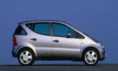 Silver compact car parked against a plain blue background.