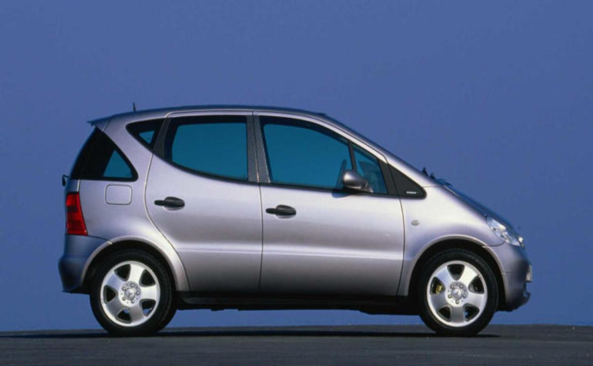 Silver compact car parked against a plain blue background.