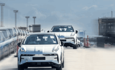 Three white electric cars driving in a line on a test track.