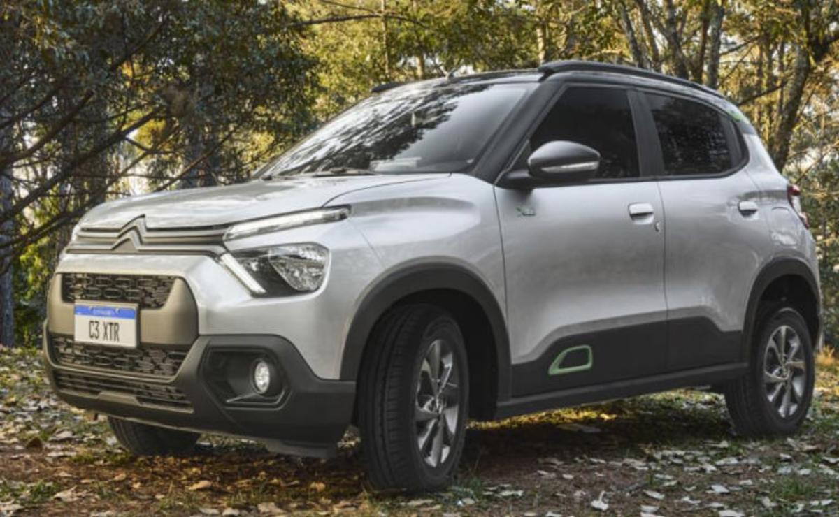 A silver SUV parked on a leaf-covered ground in a wooded area.