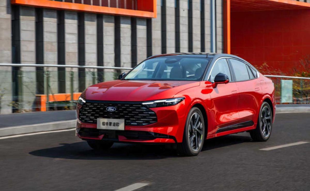 A sleek red car driving on an urban street with modern buildings in the background.