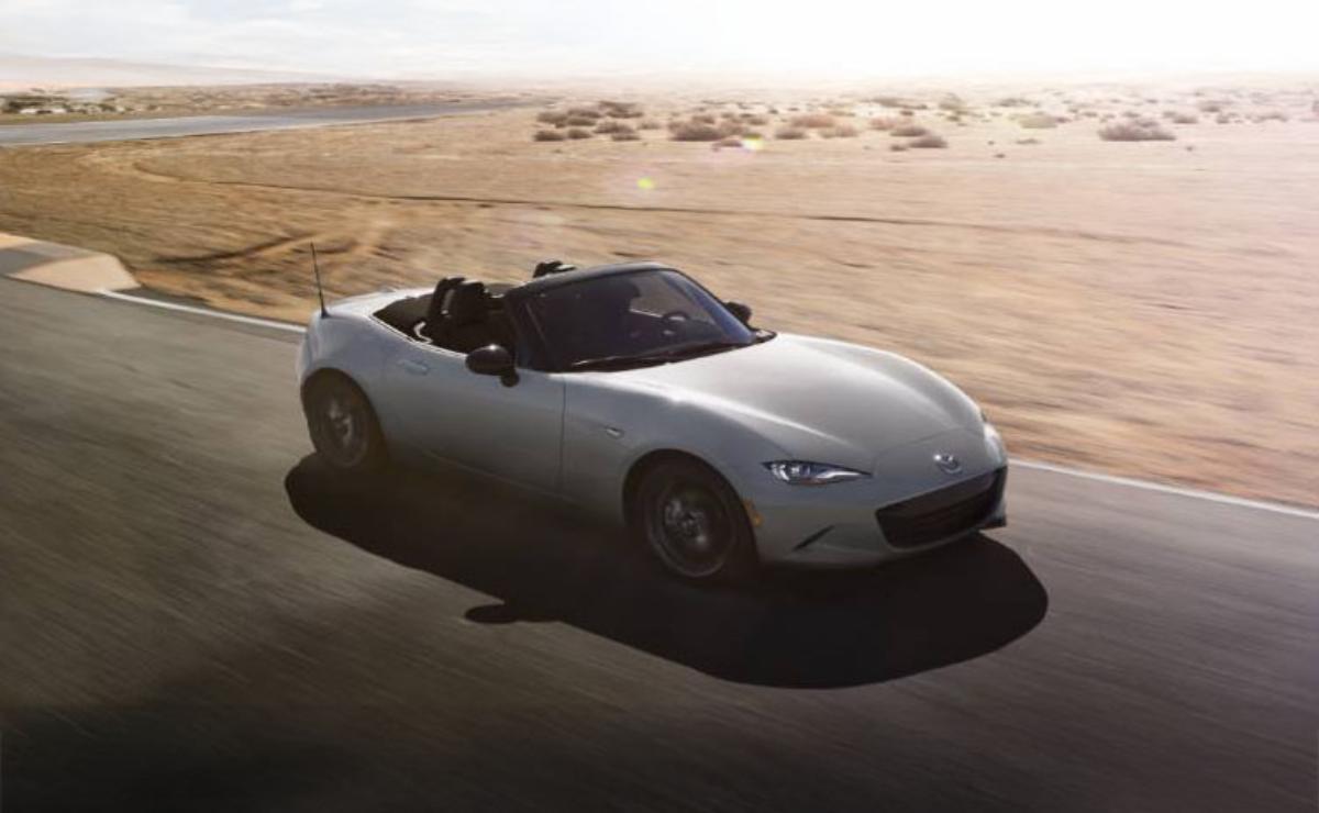 A sleek silver convertible sports car parked on a sunlit road.