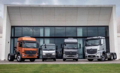 Four trucks of varying sizes parked in front of a modern building.