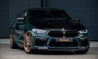 A sleek dark green BMW with bronze rims parked at night.
