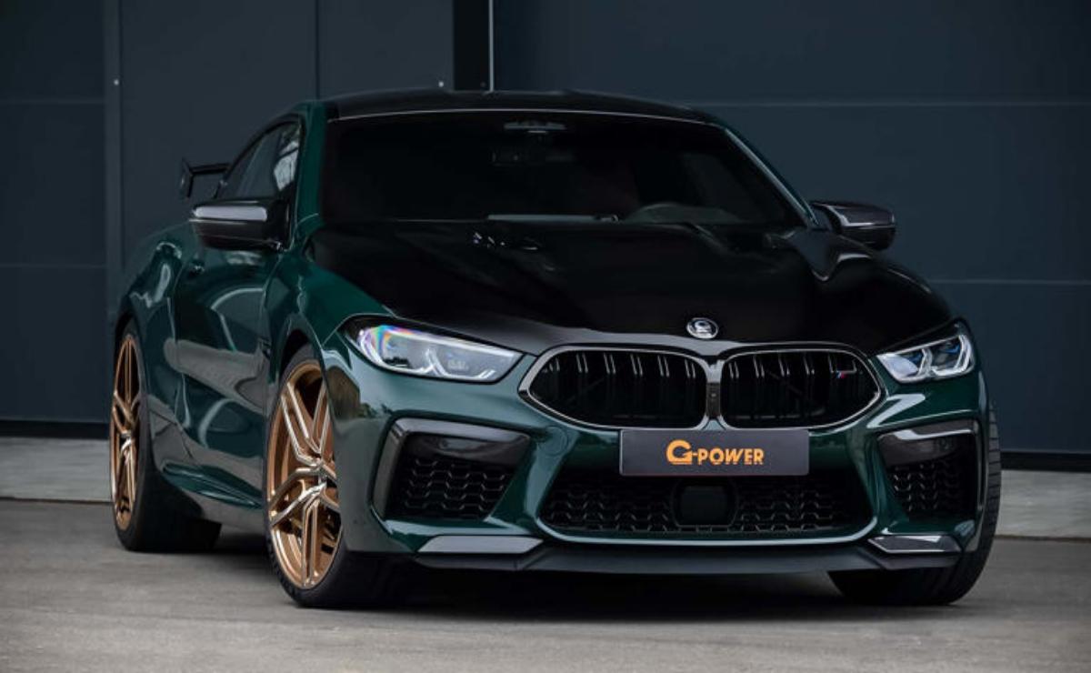 A sleek dark green BMW with bronze rims parked at night.