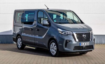A sleek gray Nissan van parked on a paved surface under clear skies.