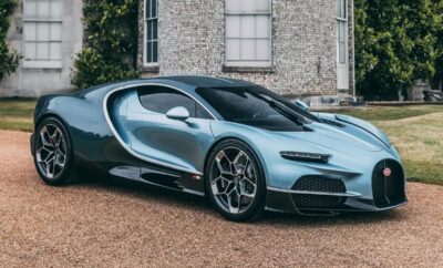A sleek blue sports car parked in front of a stone building.