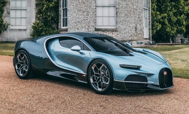 A sleek blue sports car parked in front of a stone building.