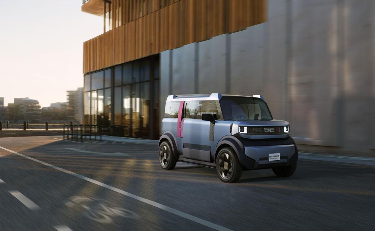 Compact electric delivery vehicle parked by a modern building at sunset.