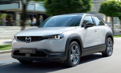 A sleek white Mazda SUV driving on a city street.