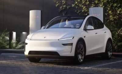 A sleek white electric car parked outdoors near a pillar.