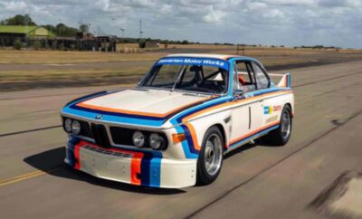 Classic BMW race car with iconic Martini racing livery on track.