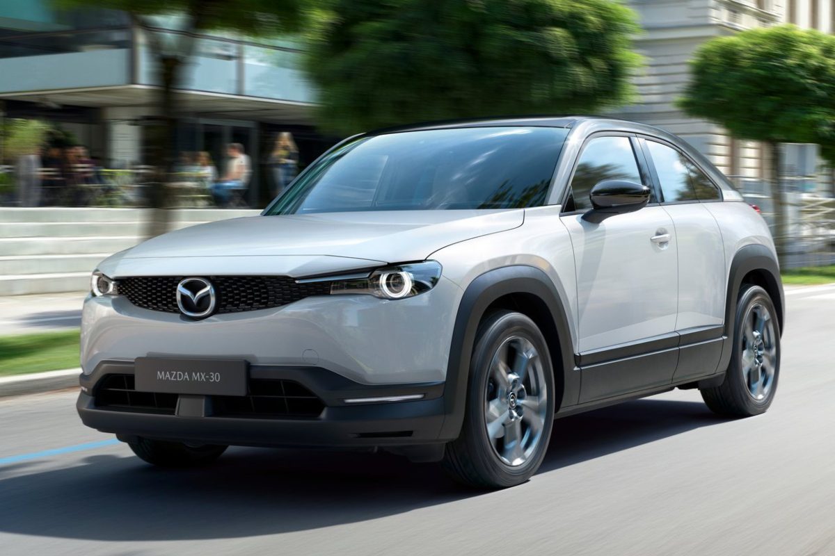 A sleek white Mazda SUV driving on a city street.