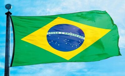 Brazilian flag waving against a blue sky.