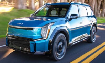 Blue electric SUV driving on a city street at dusk.