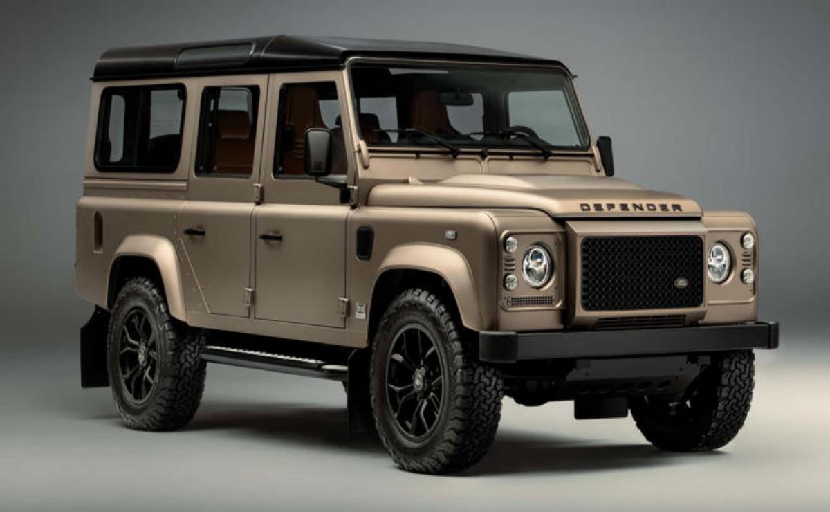 Classic beige Land Rover Defender with rugged black wheels.