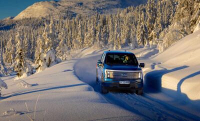 A blue SUV driving through snowy terrain in winter.