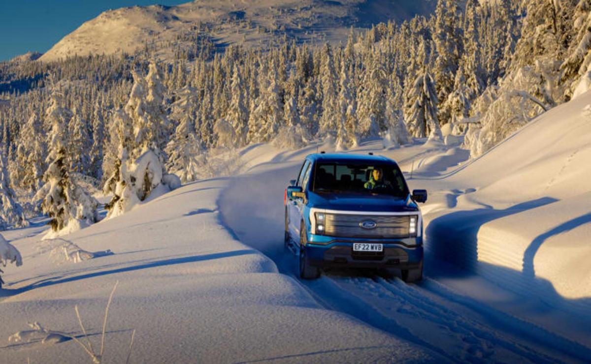A blue SUV driving through snowy terrain in winter.