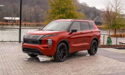 Red SUV parked on a paved area with autumn trees in the background.