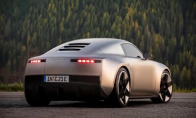 Sleek silver sports car parked with forest backdrop during dusk.