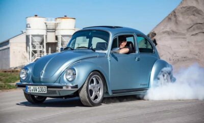 Classic blue Volkswagen Beetle performing a burnout.