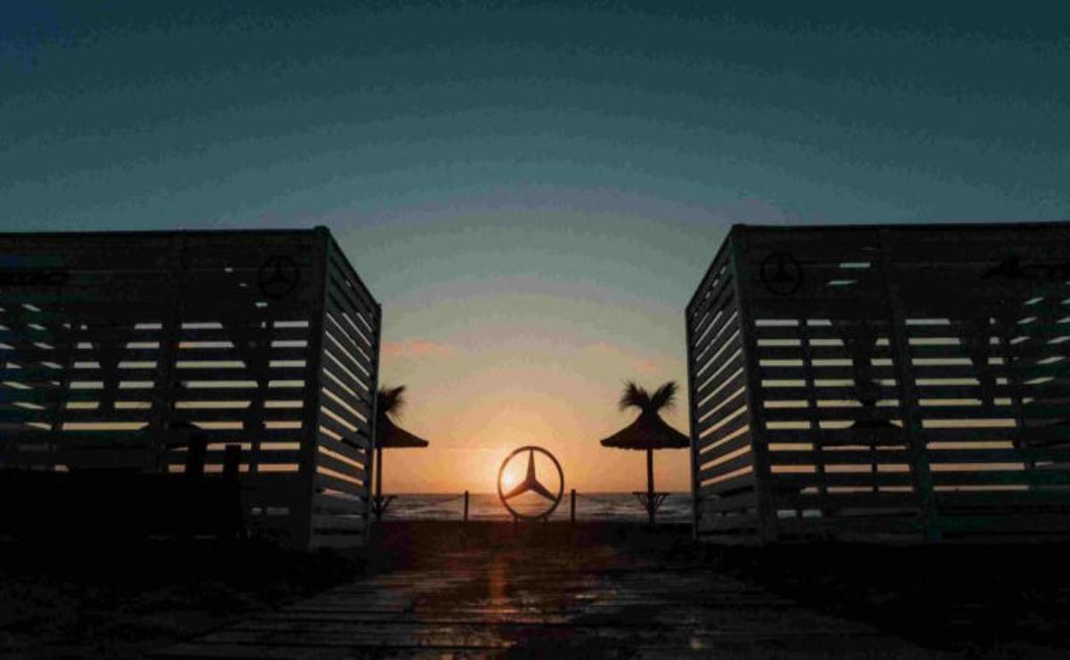 Sunset behind a Mercedes-Benz logo framed by two buildings.