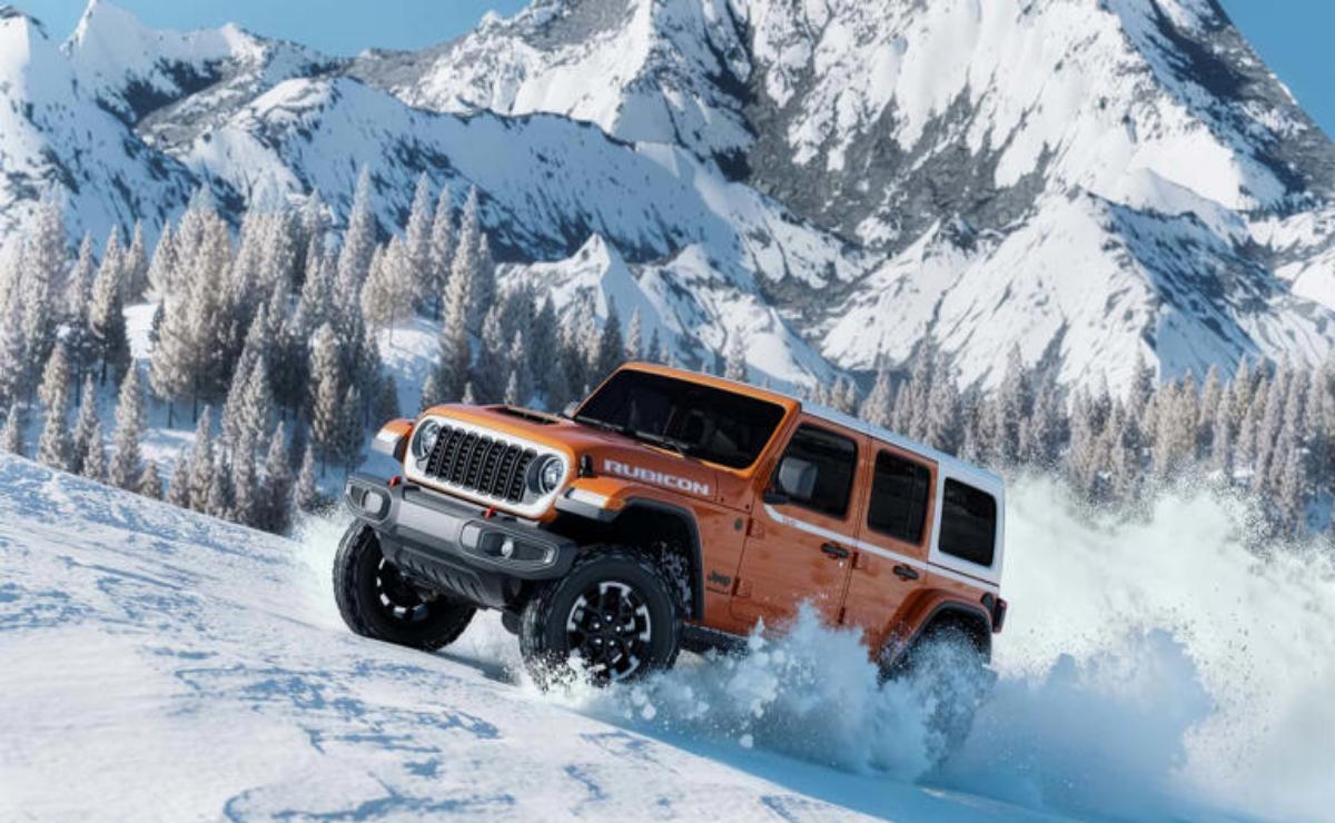 Orange off-road vehicle driving through snowy mountain terrain.