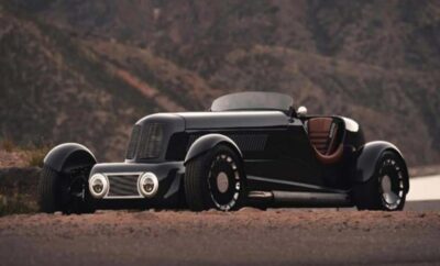 Sleek black vintage hot rod car parked on a desert road.